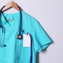 201715042-turquoise-doctor-shirt-with-stethoscope-badge-and-pen-hanging-on-light-gray-background-space-for